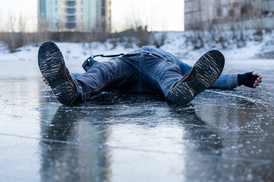 Man slipping and falling on icy ground, illustrating the danger of winter ice and the high risk of accidents during icy conditions.