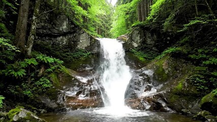 Dynamic close up of powerful waterfall currents cascading over ancient moss covered rocks, showcasing the raw energy and movement of the water. Close up perspective emphasizing the force and?