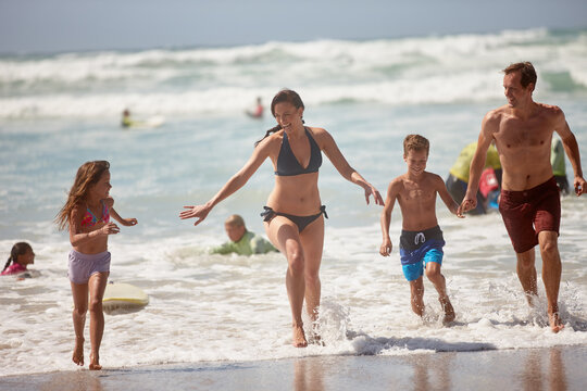 Sea, running and travel with family at beach for bonding, summer vacation and adventure. Support, holiday getaway and care with parents and children outdoor for weekend break, ocean trip and fun - Powered by Adobe