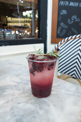 A refreshing glass of a fruit beverage, filled with ice and a sprig of rosemary