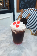 A delightful iced drink topped with cream, cookie, and heart-shaped candies, promising a sweet and refreshing treat