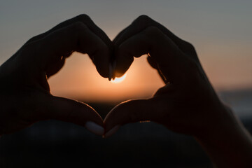 Heart Sunset Silhouette Hands - A silhouette of two hands forming a heart shape in front of a sunset.