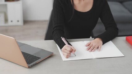 A woman studying at her desk while looking at a laptop - Powered by Adobe