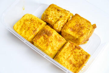 Tofu yellow spices in plastic containers for stock in refrigerator