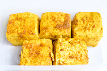 Tofu yellow spices in plastic containers for stock in refrigerator