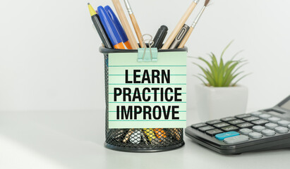 A pen holder with a piece of paper that says Learn Practice Improve on it