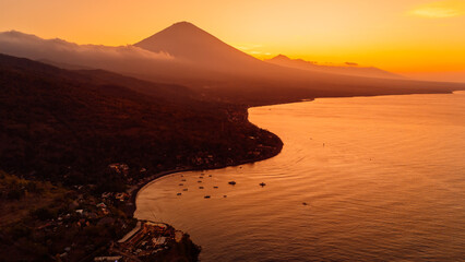 Panorama of coastline with silhouette of volcano and sunset with ocean in Bali.