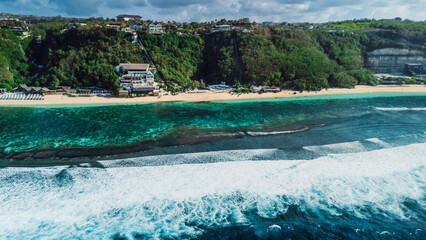 Scenic coastline with cliffs and blue ocean with waves in Bali. Aerial view