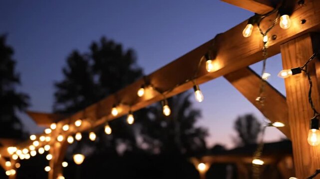 Hands install outdoor string lights on wooden structure for evening ambiance