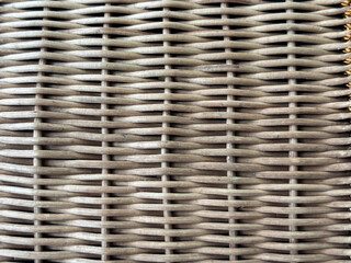 Close-up texture of woven rattan material in natural brown color. A detailed pattern of handwoven fibers creating a rustic and organic surface, commonly used for furniture, baskets, or home decor.