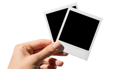Hand holding two blank instant photo frames against a black background