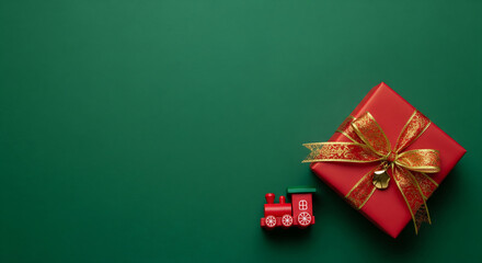 Holiday season background with copy space concept with a vibrant red gift box and toy train on a classic green paper 