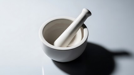 White ceramic mortar and pestle on a light gray surface with dramatic shadow