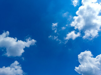 Gentle white clouds drift across a bright blue sky, creating a calm and airy atmosphere. Perfect as a clean natural backdrop for visual projects, designs, or presentations.