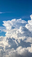 Vast cumulonimbus clouds against a bright, expansive blue sky