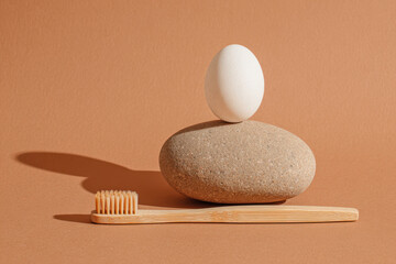 Elegant bamboo toothbrush and egg on stone, calm balanced composition