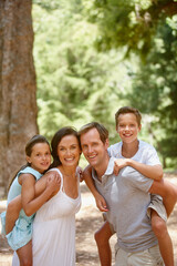 Portrait, parents or children in woods with piggyback, connection or bonding on summer break. Smile, space or people in forest with care, happy family or childhood development in spring getaway.