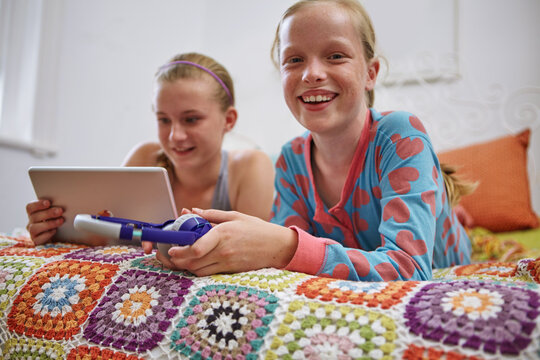 Portrait, children and tablet on bed with headphones for playing game, bonding together or entertainment. Girls, smile and digital tech in bedroom for online gaming, friendship and internet in house.