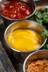 Bright yellow mustard sauce in metal cup closeup