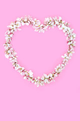 Beltane apple blossom heart shape natural wreath decoration on pink. Symbol of love for Mothers Day, Valentines, birthday, wedding, baby birth greeting card.
