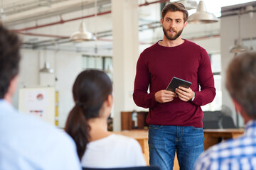 Presentation, tablet and businessman in office with planning at meeting for creative project with team. Startup, discussion and magazine editors at publishing seminar in workplace with collaboration.
