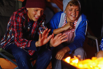 Obraz premium Camping, fire and smile with children outdoor together for adventure, bonding or survival at night. Dark, flame and heat with happy kids at campsite for holiday, travel or vacation as friends
