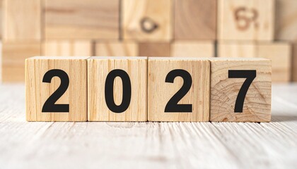 Wooden blocks forming &ldquo;2027&rdquo; on natural wood surface with green foliage background