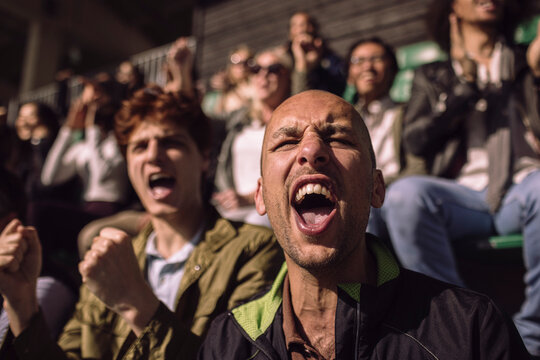 Ecstatic bald man screaming while enjoying game from stadium stand