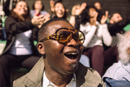 Headshot of shocked mature man wearing eyeglasses watching game in stadium