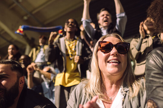 Mature female spectator wearing sunglasses watching game in stadium