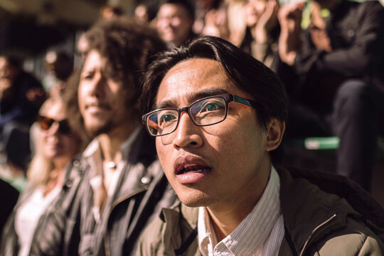 Male supporter wearing eyeglasses in shock while watching game at stadium