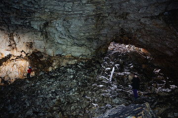 Caving gear descent, Explorer equipped with safety gear navigating rocky underground passages, Adventurer using specialized equipment to safely descend and explore rugged cavern interiors