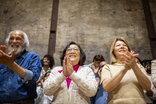 Low angle view of multiracial senior male and female spectators giving standing ovation in theater