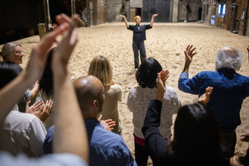 High angle rear view of male and female spectators giving standing ovation to performer after play in theater