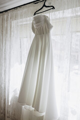 Full-length white wedding gown on hanger
