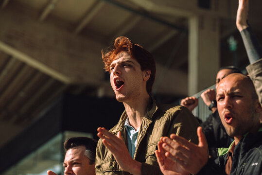 Enthusiast male fan cheering while shouting at sports stadium on sunny day