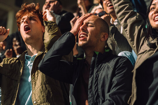 Disappointed man with hand on head at sports stadium stand on sunny day