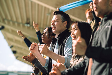 Anticipated male spectator holding fist while watching game from stadium stand