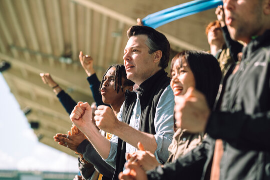 Anticipated male spectator holding fist while watching game from stadium stand