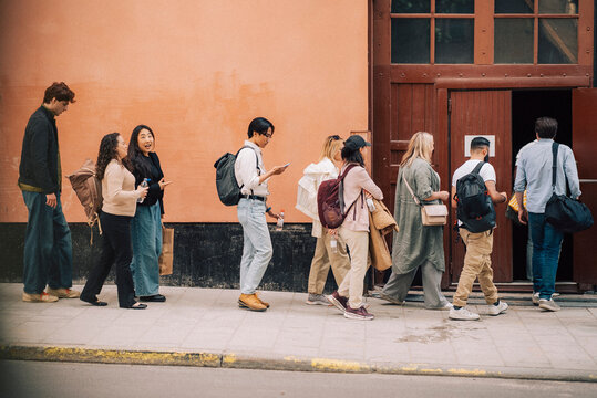 Multiracial people walking in row towards stage theater door