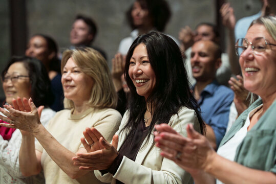 Smiling mature woman giving standing ovation in stage theater