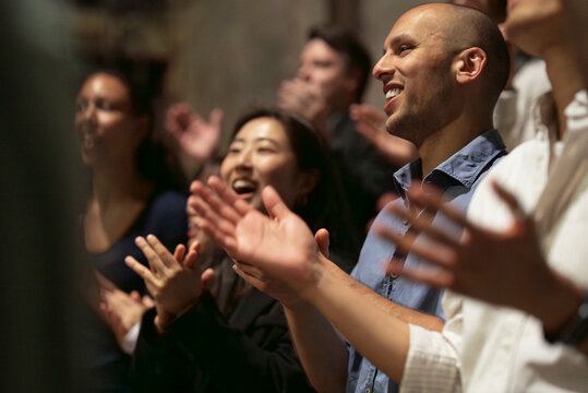 Happy bald man giving standing ovation at stage theater