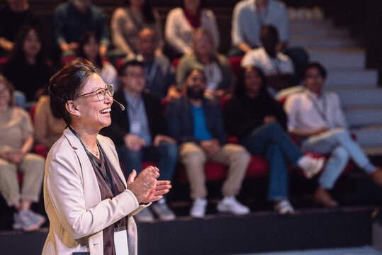 Happy mature female presenter at seminar in theater