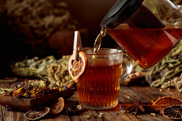 Hot herbal tea is poured into a glass mug.
