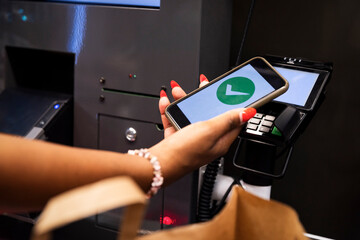 Hand of woman using mobile payment at self checkout machine in supermarket