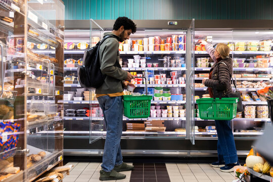 Male and female customers shopping at refrigerated section in supermarket