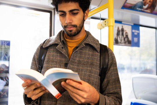 Concentrated male reader reading book in bus