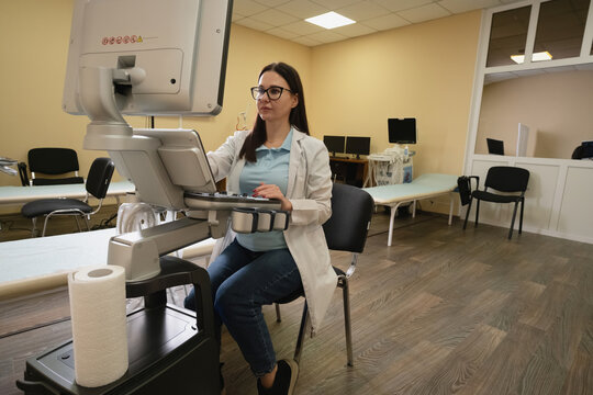 Female sonographer operating modern ultrasound equipment, conducting medical diagnosis in a bright clinic examination room, representing healthcare technology and diagnostic services