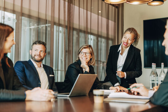 Smiling male and female business colleagues talking with each other in meeting at law office