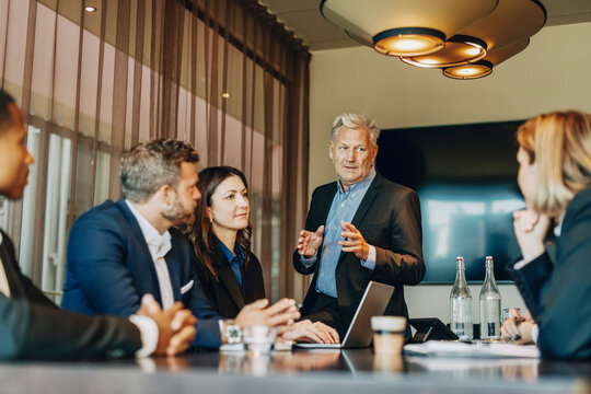 Senior businessman explaining ideas to coworkers in meeting at law office